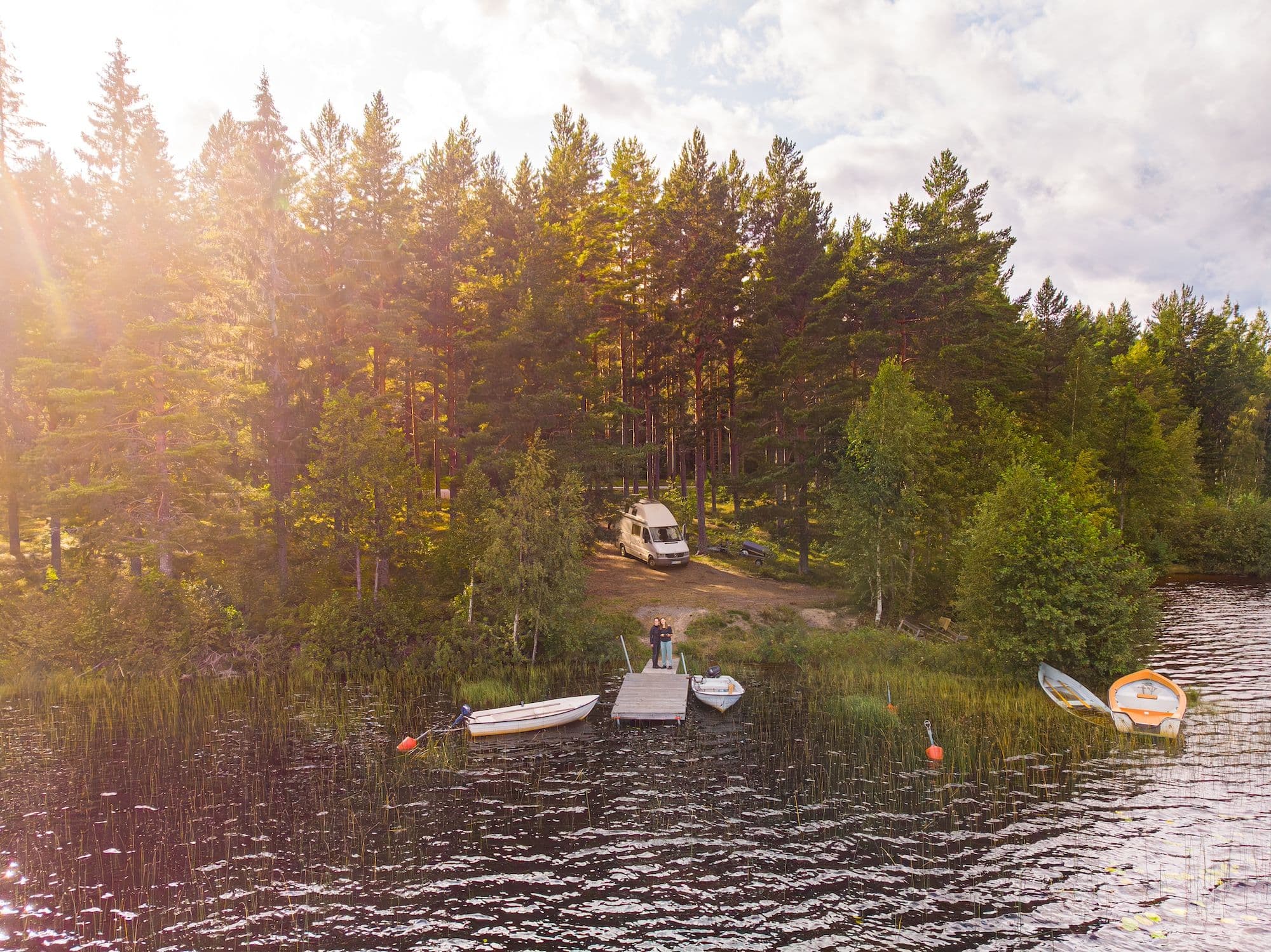 Ein weißer Mercedes Sprinter Camper steht im Wald vor einem See beim Wildcampen in Schweden